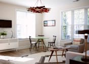Thumbnail 5 of 19 - A living room with a white cabinet, a black TV, a wooden table and chairs, and a red light fixture.