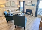 Thumbnail 7 of 15 - A living room with a white couch and a grey armchair at River Ridge Apartments in Asheville, NC