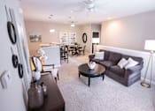 Thumbnail 9 of 20 - A living room with a couch, a dining table, and a ceiling fan.