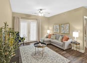 Thumbnail 1 of 14 - A living room with a couch, a coffee table, and a ceiling fan.