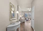 Thumbnail 5 of 19 - A well-lit, spacious living room with a white sofa set and a large mirror on the wall at Heights at New Garden apartments in Greensboro, NC.