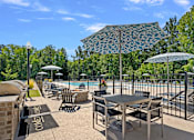Thumbnail 16 of 54 - A poolside area with chairs, tables, and umbrellas.