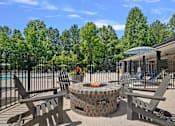 Thumbnail 6 of 52 - A fire pit sits in the middle of a patio surrounded by chairs.