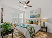 Thumbnail 24 of 52 - A bedroom with a bed, a ceiling fan, and a painting on the wall.