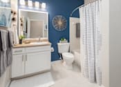 Thumbnail 25 of 27 - A bathroom with blue walls, a single sink, bathtub and toilet.
