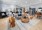 Thumbnail 2 of 27 - Clubhouse interior with a seating area of a couch and chairs surrounding a wooden coffee table.