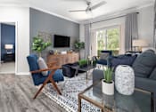 Thumbnail 19 of 27 - A living room with a blue chair, a grey couch, and a coffee table.