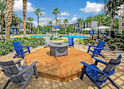 Thumbnail 12 of 27 - A poolside area with an outdoor firepit and five chairs surrounding.