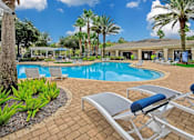 Thumbnail 5 of 27 - Outdoor pool surrounded by palm trees and lounge chairs.