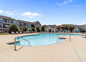 Thumbnail 2 of 19 - A large swimming pool surrounded by lounge chairs and buildings in the background at Heights at New Garden apartments in Greensboro, NC..