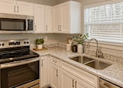 Thumbnail 1 of 15 - A kitchen with a stove, microwave, and sink.