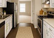 Thumbnail 2 of 15 - A kitchen with white cabinets and a brown rug on the floor.