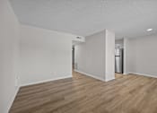 Thumbnail 10 of 52 - A room with wooden flooring and white walls and a view into the kitchen.