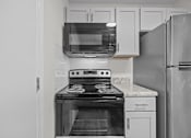 Thumbnail 26 of 52 - Kitchen with a black stove, microwave, and refrigerator nearby.