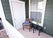 Thumbnail 15 of 20 - A white door is on the left of a porch with a chair and a small table.