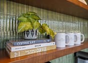 Thumbnail 2 of 17 - A shelf with books and mugs on it.