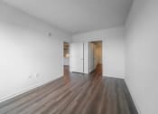 Thumbnail 25 of 34 - an empty living room with white walls and wood flooring