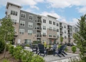 Thumbnail 5 of 14 - an outdoor patio with chairs and tables in front of the apartment building at Enclave Crystal Lake, 60014