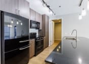 Thumbnail 39 of 41 - a kitchen with black countertops and stainless steel appliances