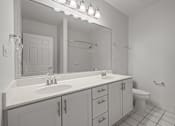 Thumbnail 12 of 17 - A bathroom with a sink, mirror, and toilet.
