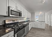 Thumbnail 11 of 17 - A modern kitchen with a stove, microwave, and oven.