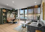 Thumbnail 10 of 17 - A modern living room with a grey sofa, wooden chairs, and a glass table.