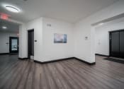 Thumbnail 9 of 34 - a large room with white walls and wooden floors and two black doors