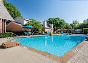Thumbnail 9 of 32 - An apartment swimming pool surrounded by a stone border and a few chairs at 1601 Eastchase Pkwy in Fort Worth, TX.