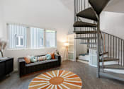 Thumbnail 22 of 52 - A living room with a spiral staircase and a black couch.