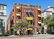 Thumbnail 32 of 51 - A red brick building with a yellow awning and a sign that says Now Leasing at Brookmore Pasadena apartments.