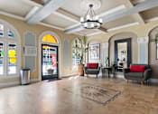 Thumbnail 30 of 51 - A spacious lobby with a chandelier, sofas, and a large rug at the Brookmore Apartments leasing office.