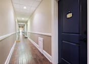 Thumbnail 13 of 51 - A hallway with a door on the right and a number 210 on the door.