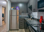 Thumbnail 7 of 25 - Kitchen in the Canvas Apartments, Downtown Nashville apts for rent with modern grey wood cabinets, white tile backsplash, and stainless steel appliances.