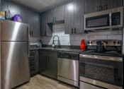 Thumbnail 9 of 25 - Kitchen in the Canvas Apartments in Nashville with stainless steel appliances and luxury grey wood cabinets that reach the ceiling.