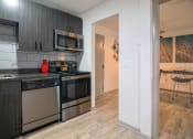 Thumbnail 8 of 25 - Kitchen in the Canvas Apartments in East Nashville with modern grey wood cabinets and stainless steel dishwasher, microwave, and electric stove.