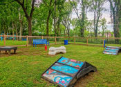 Thumbnail 18 of 25 - The Canvas apartments dog park with agility course, fire hydrant, blue park bench, and wood and chainlink fencing.