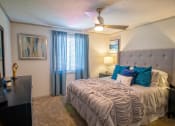 Thumbnail 12 of 49 - Bedroom in the Retreat at Indian Lake apts in Hendersonville with modern ceiling fan, queen bed, and large window with blinds and curtains.