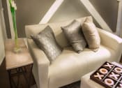 Thumbnail 3 of 29 - Brookmore apartments Pasadena - Modern Cream Sofa with grey and cream throw pillows, End Table with tall flower vase, and Hardwood-Inspired Flooring in living room sofa area