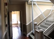 Thumbnail 21 of 29 - Pasadena Brookmore apartments stairwell with carpeted stairs, dual tone walls in dark and light tan with white trim, and dark wood inspired flooring