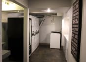 Thumbnail 22 of 29 - Pasadena Brookmore apartments on site laundry room with eight washers and dryers and a black vending machine on concrete floors