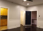 Thumbnail 8 of 29 - Living room in brookmore apartments in Pasadena featuring dark wood flooring and white wainscoting. Open doorways lead to the kitchen and front closet.