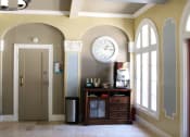 Thumbnail 25 of 29 - Lobby in Brookmore Apartments in Pasadena with large arched windows and coffee station.