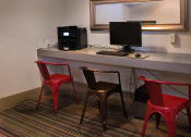 Thumbnail 6 of 29 - Brookmore Pasadena apartments computer lounge with wifi, a dell computer, and printer set up on a counter with two red stools and one black stool.