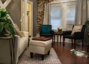 Thumbnail 1 of 29 - Pasadena Brookmore Suite with cream sofa, small sitting area by window, an open door to kitchen, and Exposed Brick Wall