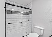 Thumbnail 13 of 27 - The Canvas Apartments Nashville bathroom with a white toilet and white tile shower.