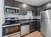 Thumbnail 3 of 27 - The Canvas one and two bedroom apartments Nashville modern kitchen with stainless steel appliances and wooden cabinets.