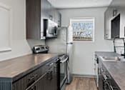 Thumbnail 11 of 27 - The Canvas Nashville apartments modern kitchen with dark wood cabinets and stainless steel appliances.