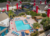 Thumbnail 41 of 60 - Aerial shot of community pool surrounded by Fusion Orlando apartment buildings. Buildings are two stories and have red chimneys and stairwells.
