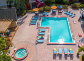 Thumbnail 39 of 60 - Aerial view of L-shaped community pool at Fusion Apartments in Orlando, FL. Pool is next to pool house, wood trellis, and round hot tub.