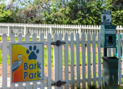 Thumbnail 29 of 49 - Pet park at the Retreat at Indian Lake apts in hendersonville with dog waste station and white picket fence with "Bark Park" sign.